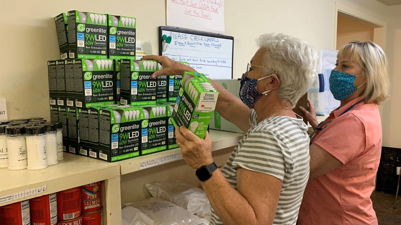 Volunteers Roxanne McIngvale (right) and Debra Sikes stock shelves with energy-efficient light bulbs at Interfaith Council on Poverty in Hernando. 